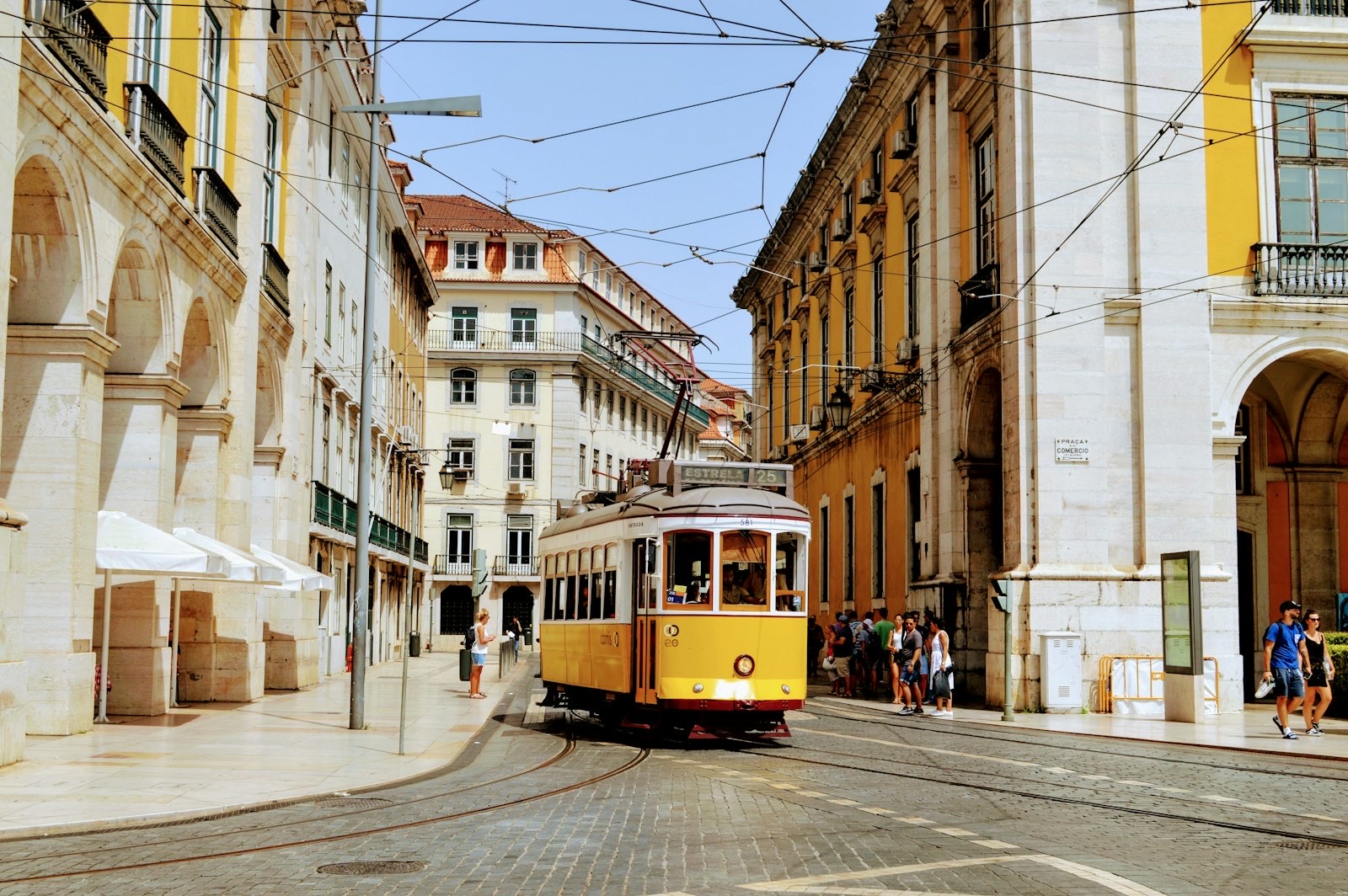 El&eacute;trico amarelo passando pelas ruas hist&oacute;ricas de Lisboa, junto &agrave; Pra&ccedil;a do Com&eacute;rcio